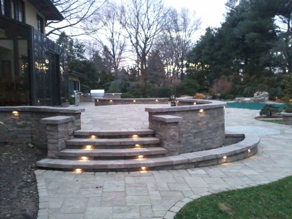 Stone paver walkway with lighted steps and decorative stone walls