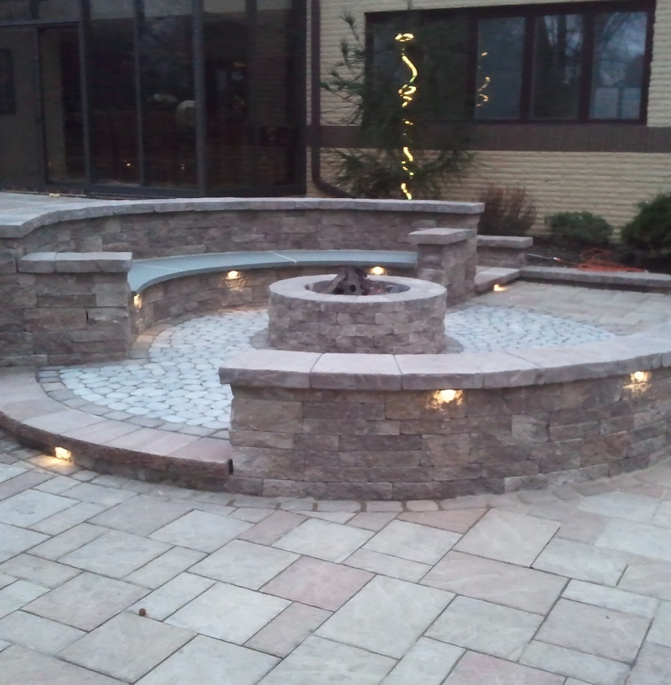Fire pit with lit decorative walls and stone benches surrounding the fire pit.