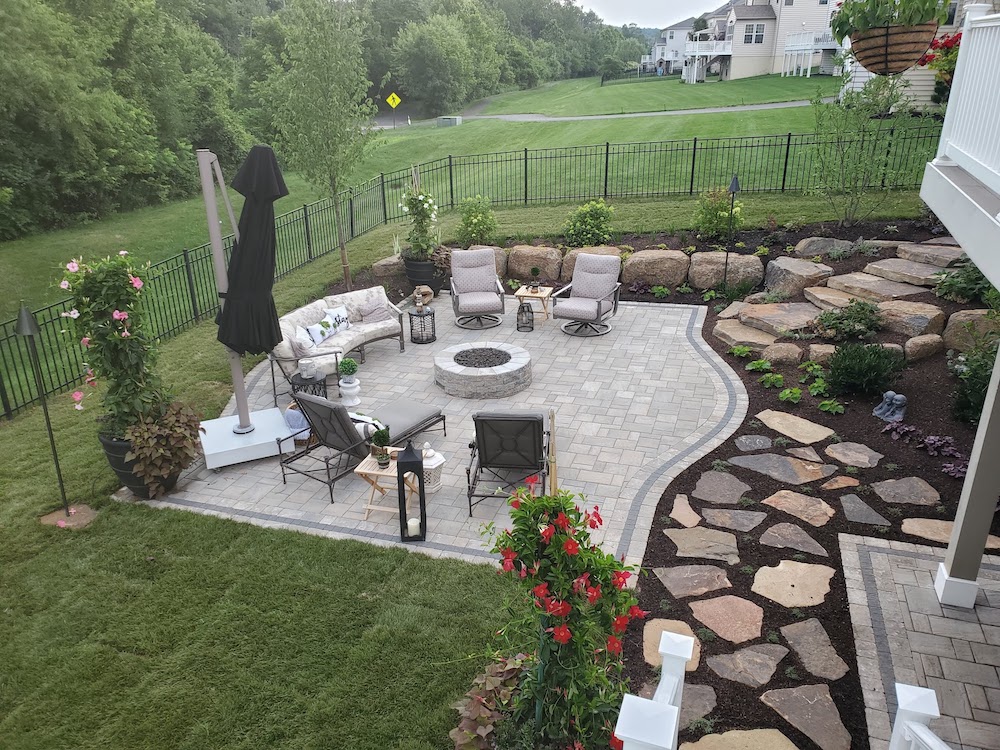Landscaped trees and stonework around a patio with fire pit