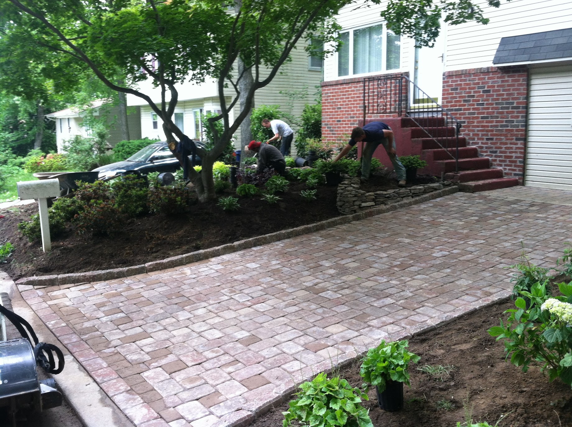Landscapers installing plants in a flower bed in front of a house