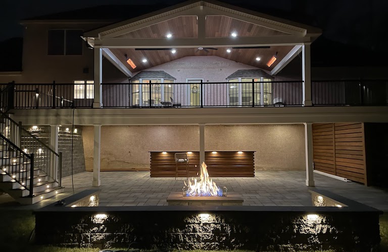 Outdoor living space with a deck, rain escape, kitchen, fire pit, and decorative walls