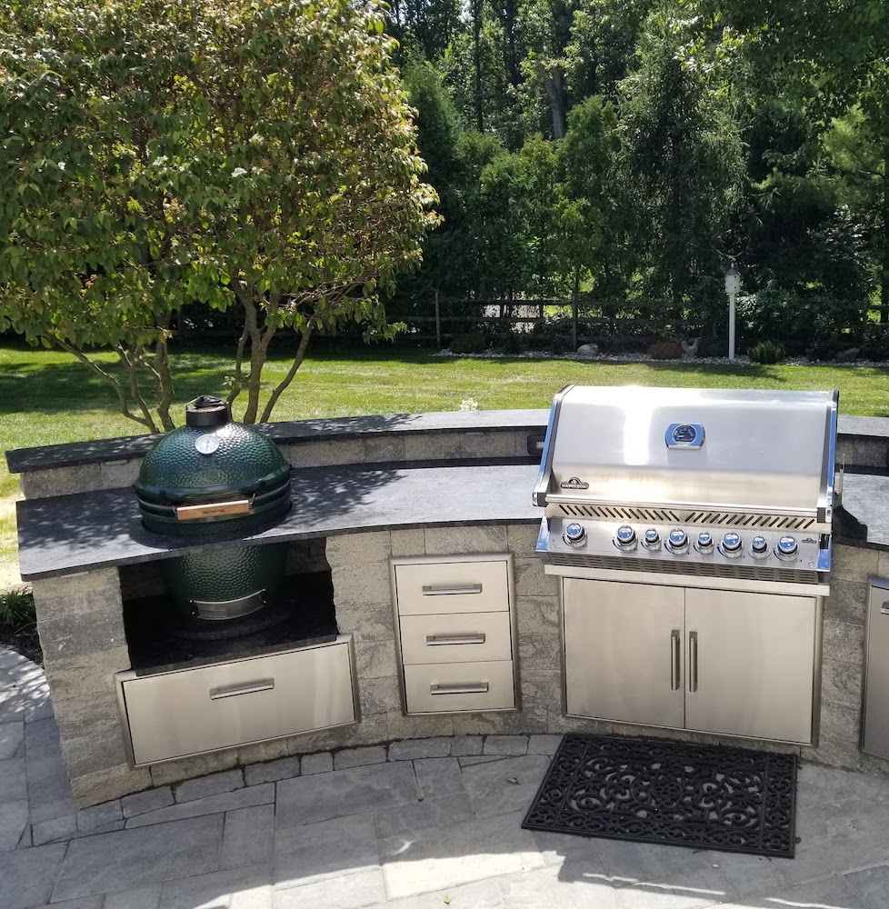 Outdoor cooking area with stainless steel grill, drawers, and green egg smoker.