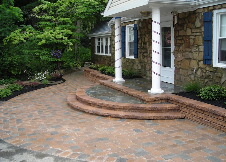 Stone patio and steps leading to columns around a front door