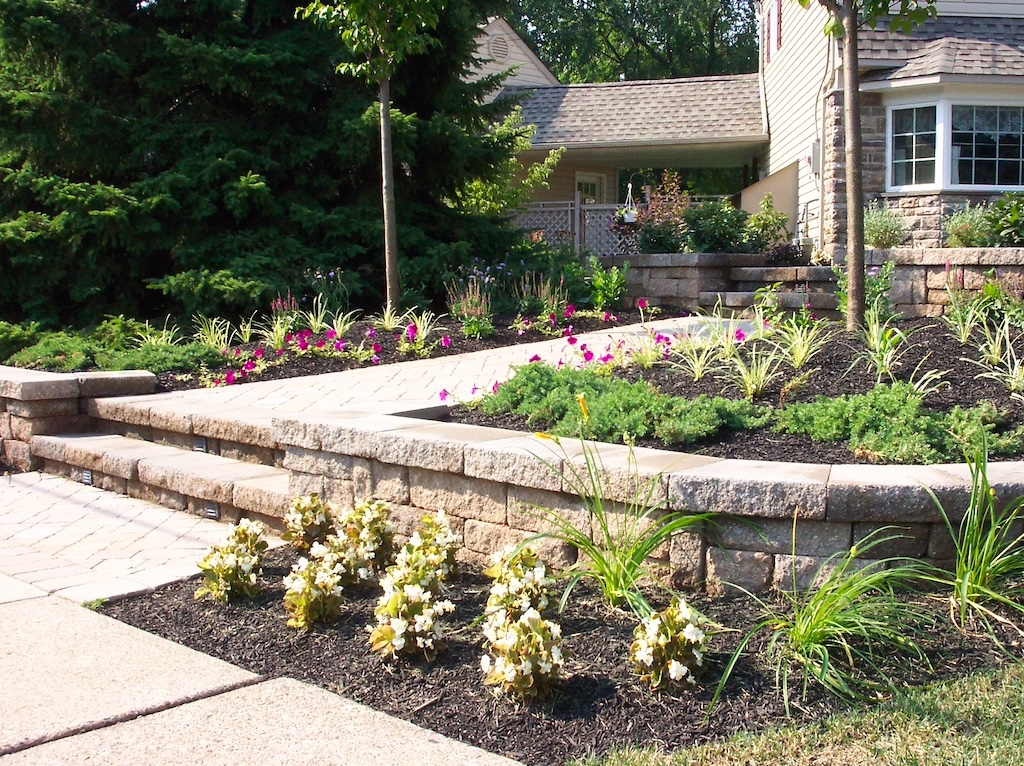 Home landscaped with stone steps, concrete paths, and stone walls.