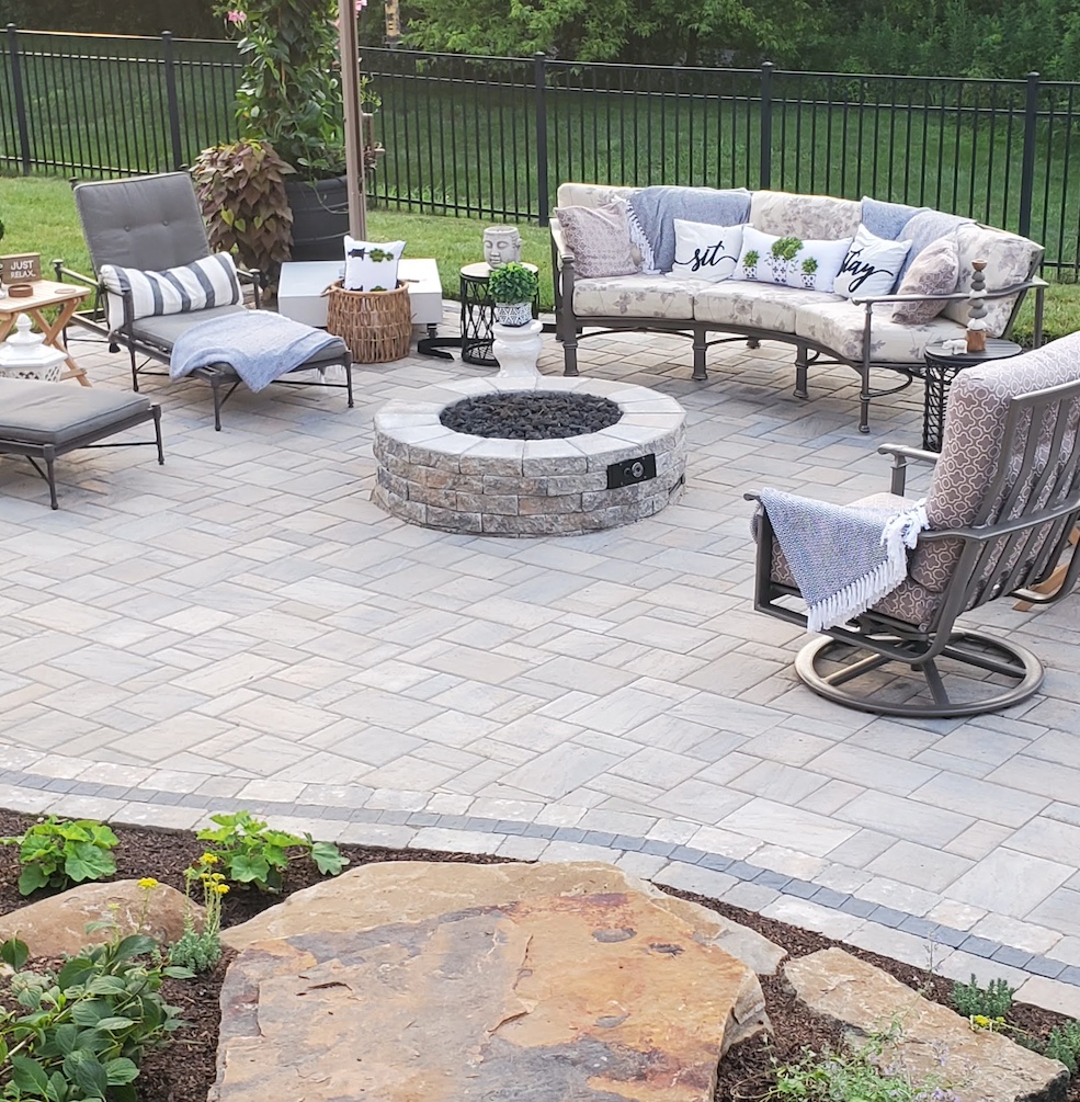 Light stone fireplace surrounded by patio and custom landscaping